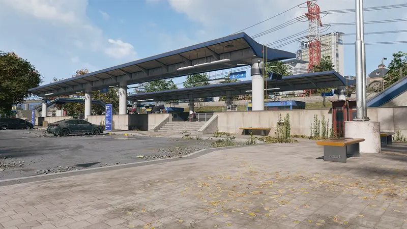 Outdoor train station with long blue platform canopies, concrete stairs, benches, and an abandoned car.