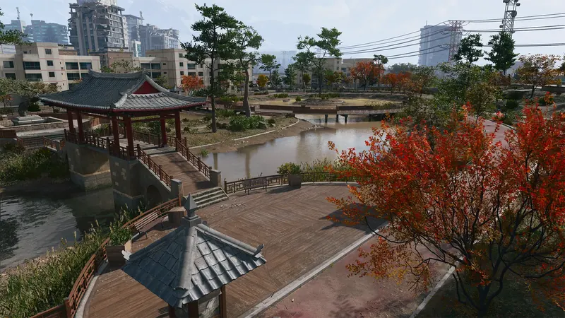 Traditional Korean pavilion overlooks a pond with wooden walkways, red autumn trees, and apartment buildings in the distance.