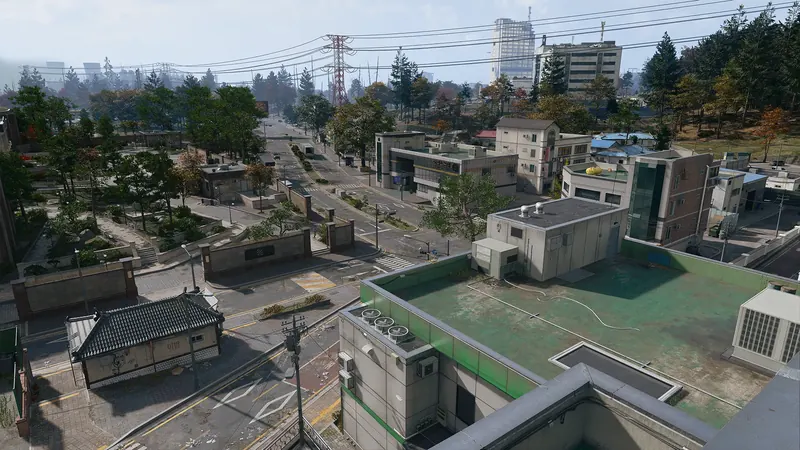 Elevated view of a quiet Korean village with tree-lined streets, low-rise buildings, and distant power lines.